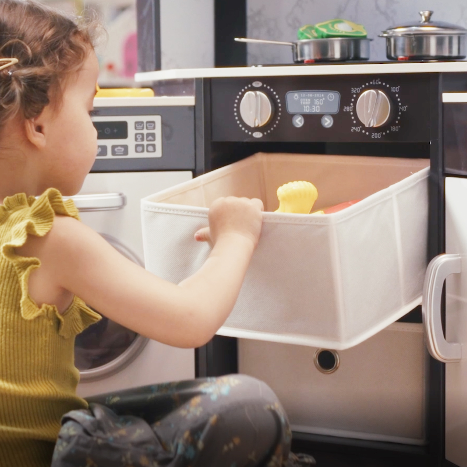 Child playing with a drawer in the Wooden Kids Play Kitchen Playset, featuring realistic lights and sounds for.